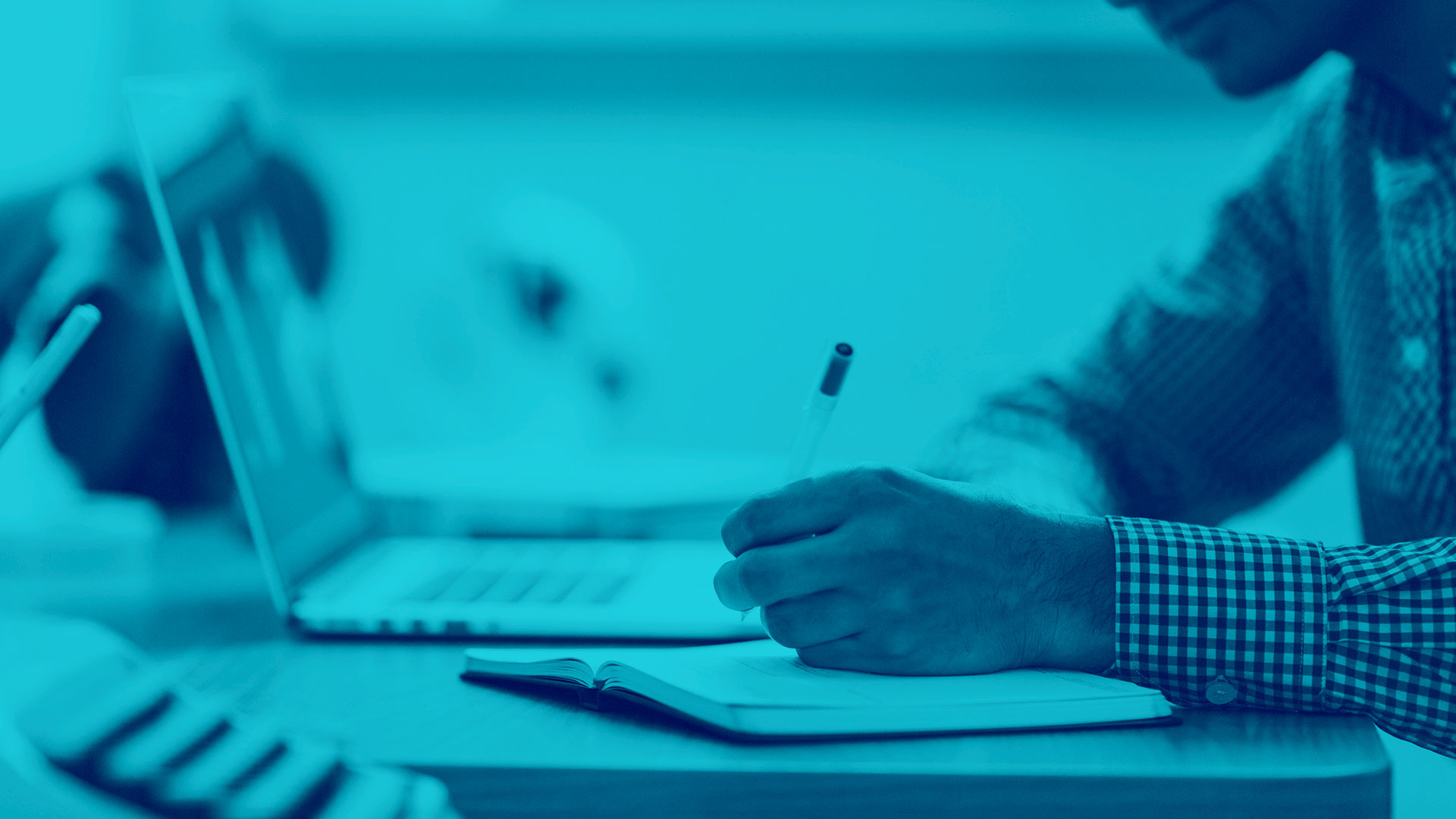 Male using his laptop and taking notes