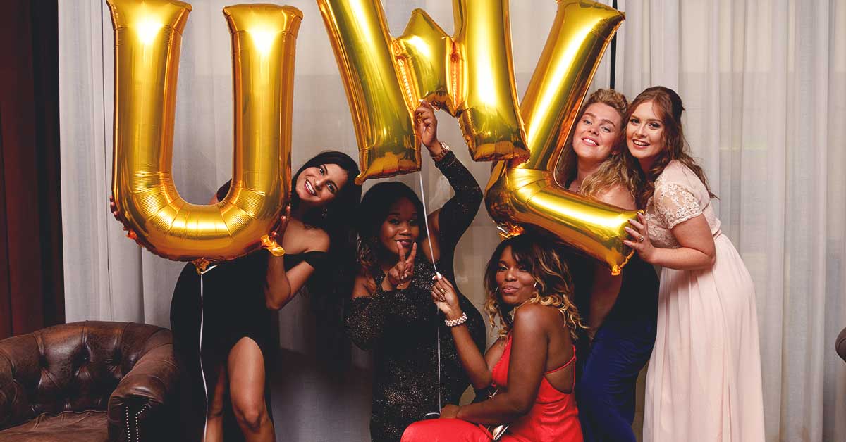 Students posing for the camera with letter balloons that real UWL