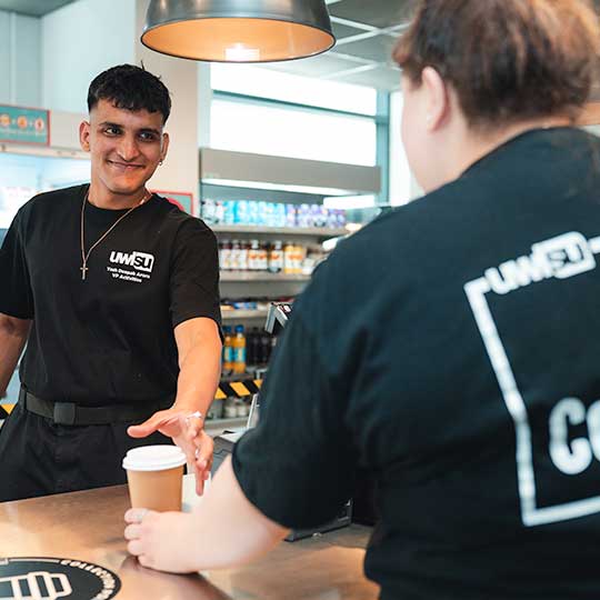 A Coffee Union staff member passing a coffee across the bar