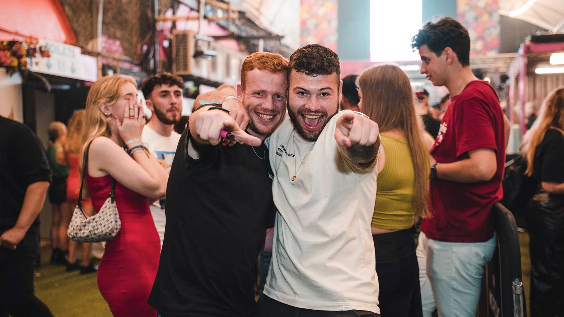 Two students posing and pointing at the camera and laughing